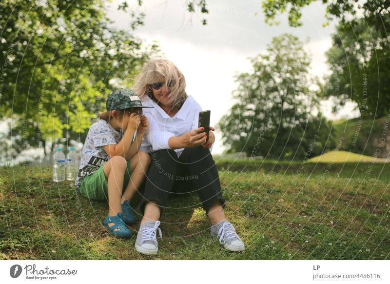 mother showing a child something on her mobile parenthood Parents focus supervision togetherness Together teaching Teacher serious solitary message