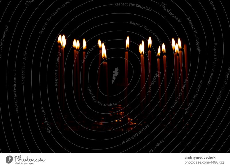 close up a lot of burning candles isolated on black background. candlelight flame fire night glow church religion christmas dark praying glowing religious