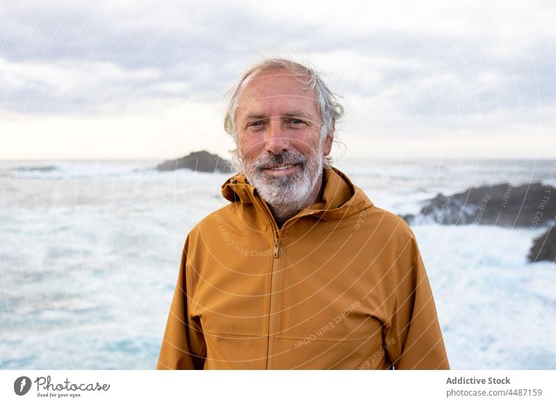 Portrait of elderly man near of the sea senior stormy wave coast seashore water traveler observe waterfront waterside seascape environment ripple scenery