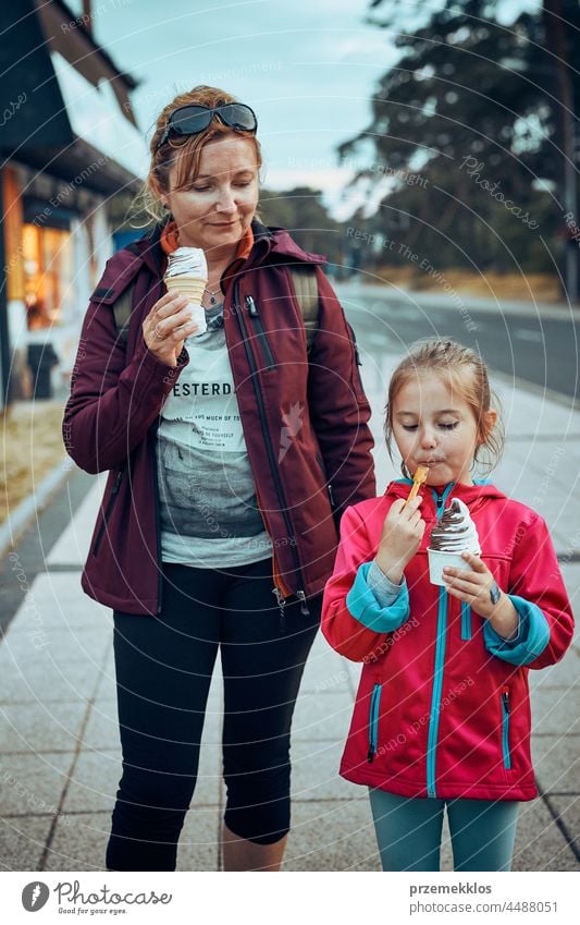 Mother and her daughter enjoying ice cream walking through town afternoon family summer sweet dessert eating person child fun mother happy togetherness parent