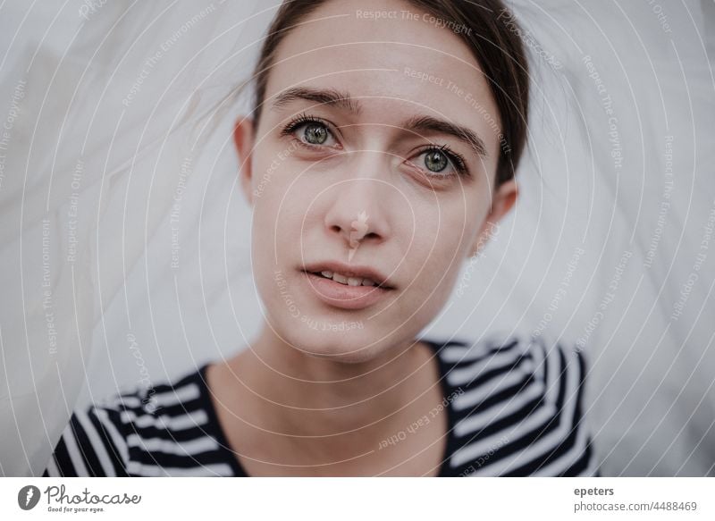 Young attractive woman with striped t-shirt underneath transparent plastic film looking into the camera adult background beautiful beauty brunette caucasian