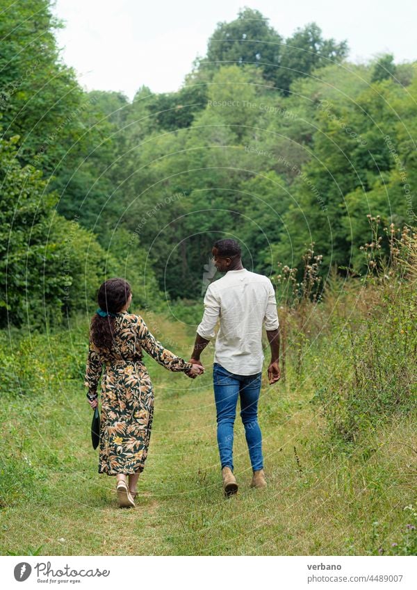 diverse ethnics couple holding hands walking in a park in fall afro caucasian love family new order culture woman people smiling outdoors smile happiness summer