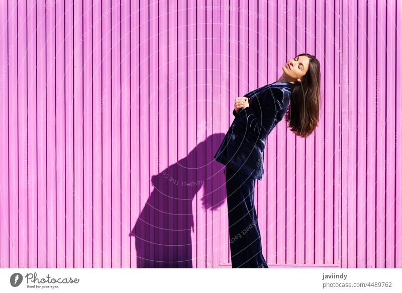 Woman wearing blue suit posing near pink shutter. woman hairstyle fashion model building blind fuchsia purple moving girl person lifestyle female urban