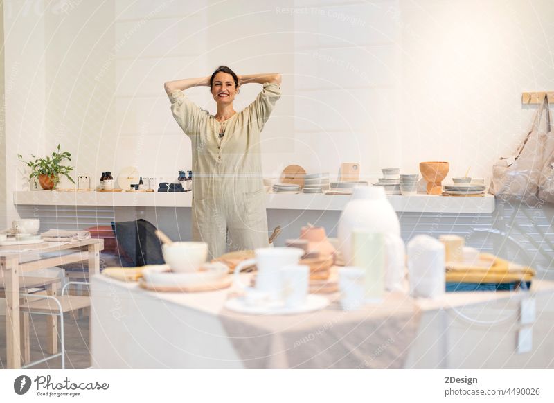 Portrait of beautiful happy craft woman wearing apron and smiling while standing in her art studio or craft pottery shop workshop ceramist occupation female