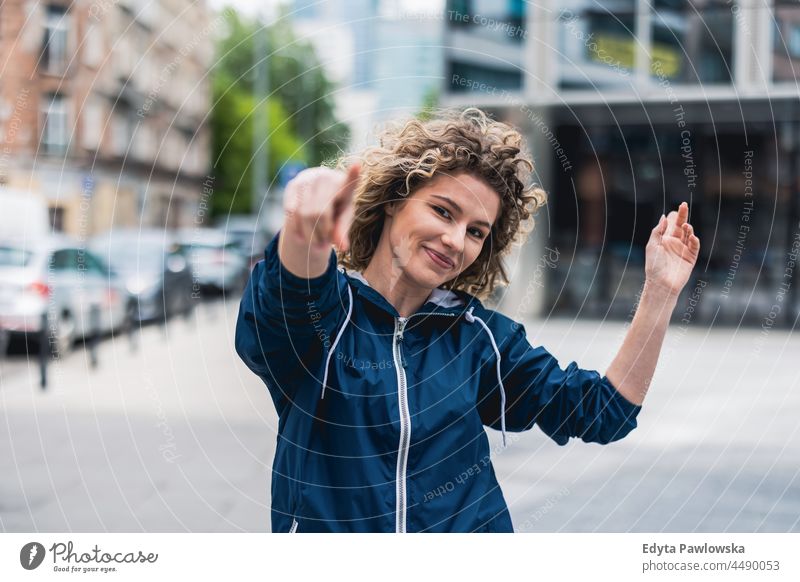 Young woman dancing in the city streets Warsaw day fun curls hairstyle summer happiness outdoors tourist beauty smiling cheerful real people city life