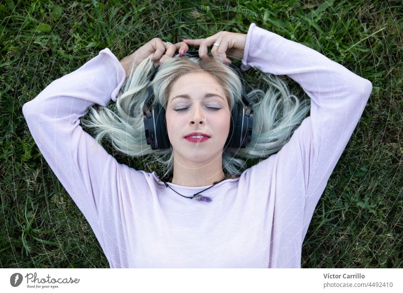 a young blonde woman chilling and enjoying music with headphones earphones person dance listen listening model relaxation smile student stylish trendy pretty