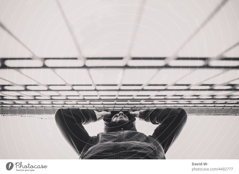 locked up - sad man stands in front of a fence penned Fence cordoned off Border hands Grief captivity Barbed wire Freedom Barrier Longing Threat Sadness Anger