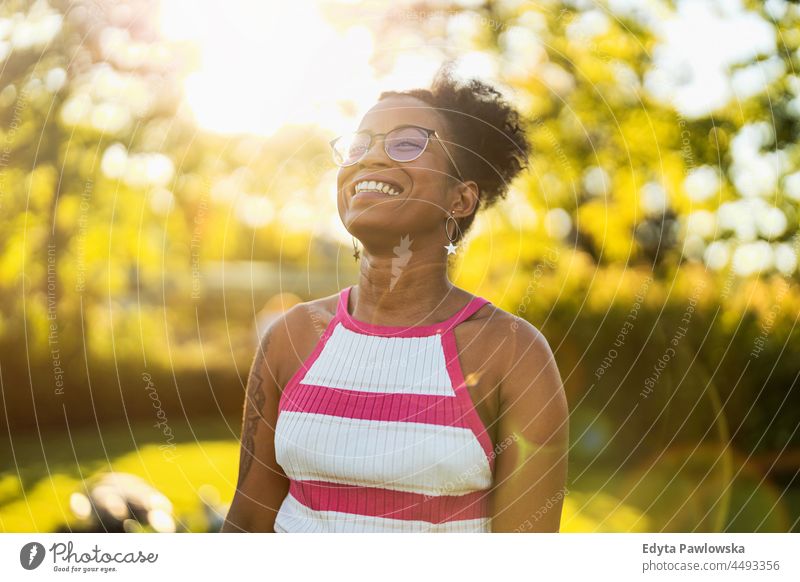 Portrait of young woman smiling outdoors at sunset millennials eyeglasses curly joy outside colorful afro confident female beauty vacation travel satisfied