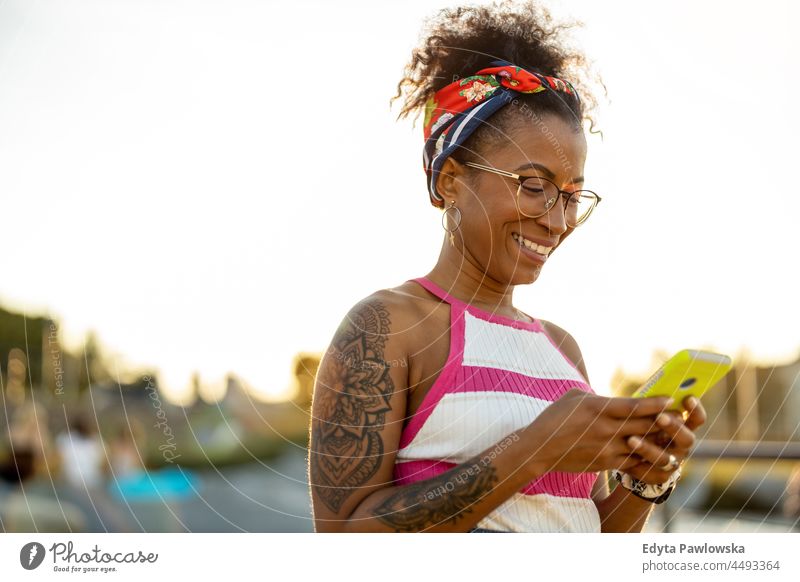 Young woman using mobile phone in the city millennials eyeglasses curly joy outside colorful afro confident female beauty vacation travel satisfied one person