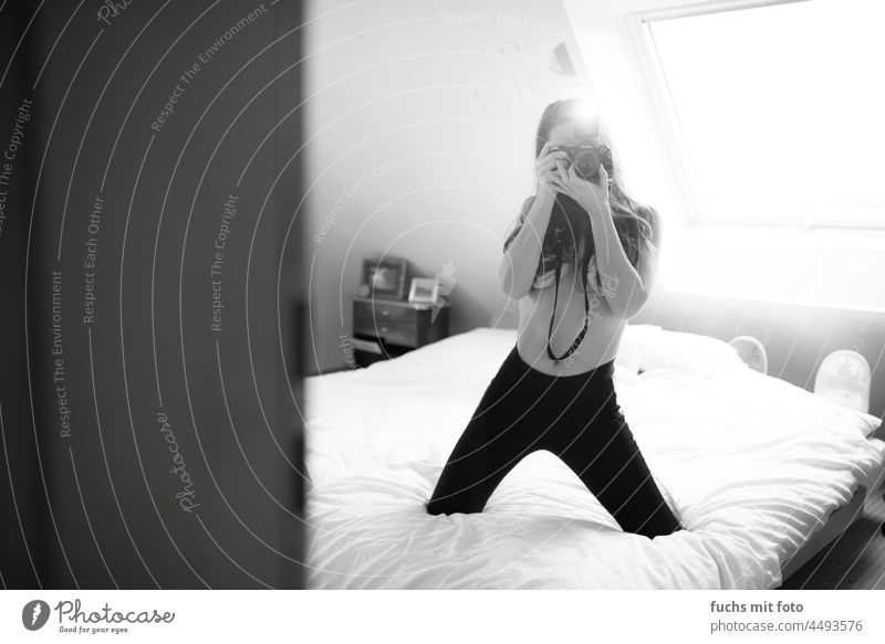 Young woman taking pictures on a bed Woman camera topless Bed Long-haired flash Feminine Interior shot Looking into the camera portrait 18 - 30 years Leggings