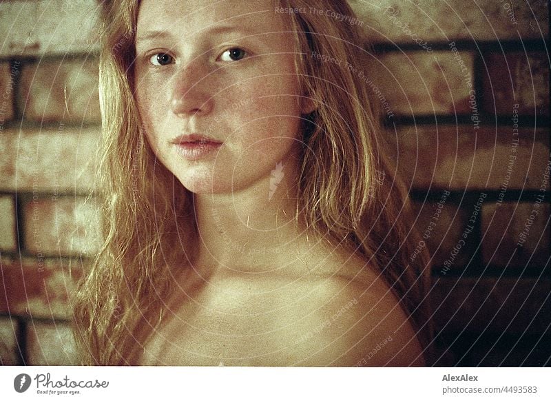 analogue portrait of a young woman with freckles and red hair standing in front of a brick wall Near proximity Emanation tranquillity vigorous pretty