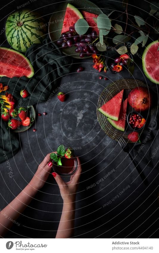 Unrecognizable woman with refreshing drink on table with watermelon beverage basil strawberry vitamin healthy food pomegranate refreshment grape organic natural