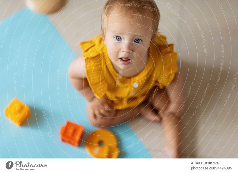 little caucasian baby girl ten months old playing with educational silicon toys at home or nursery. Child having fun with colorful toys on white background