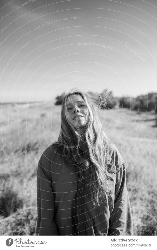 Woman standing on grassy meadow woman nature summer sky cloudless countryside environment peaceful female field flora alone shirt calm daytime bush plant lawn