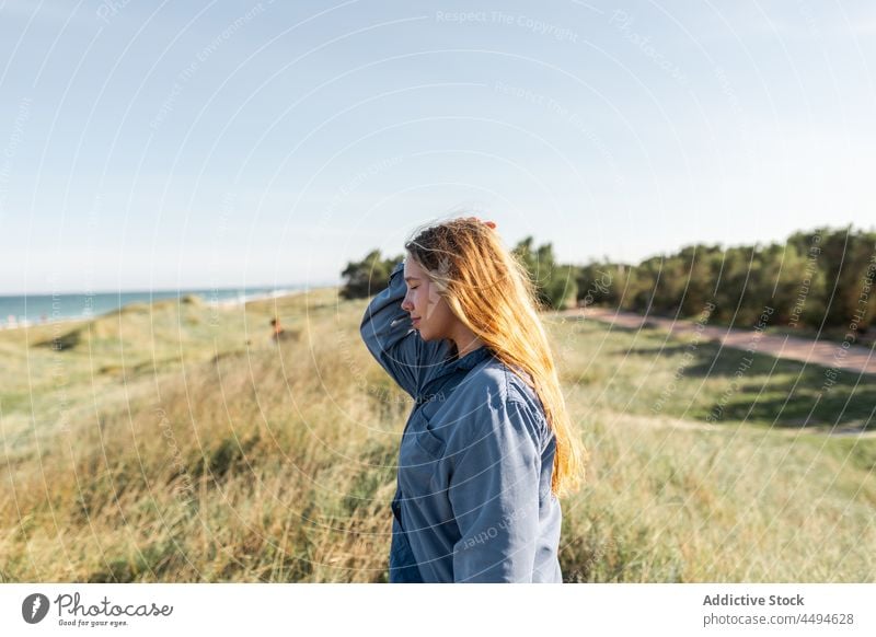 Pensive woman standing in grassy meadow summer happy nature field peaceful smile glad female delight fun pensive young lawn thoughtful countryside positive