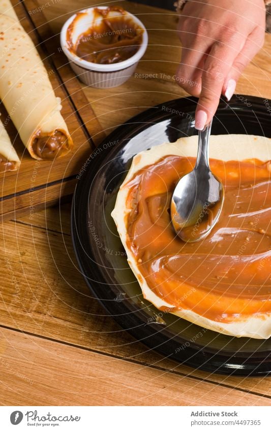 Unrecognizable woman spreading Dulce de leche on crepe dulce de leche cook sweet dessert treat culinary homemade cuisine food chef tasty serve delicious kitchen