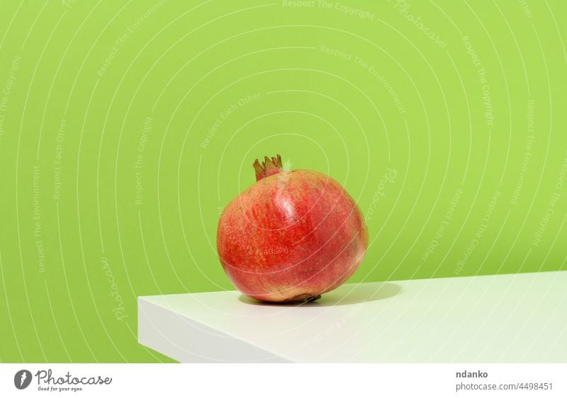 whole ripe red pomegranate on white table, green background fruit food healthy juicy vegetarian sweet freshness tropical raw organic vitamin juice natural