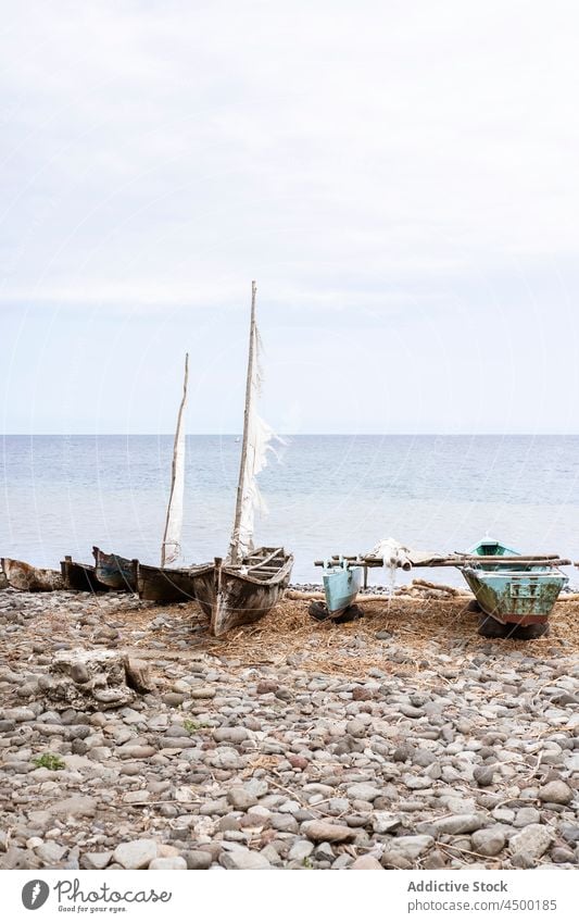 Wooden boats on rocky shore of ocean coast moor calm old nature aged São Tomé and Príncipe africa cloudy wooden beach picturesque cliff sea forest daylight