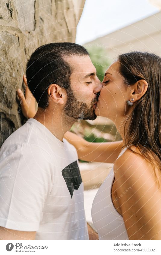 Loving ethnic couple kissing near wall of building on street embrace eyes closed love stone romantic relationship affection together city date boyfriend