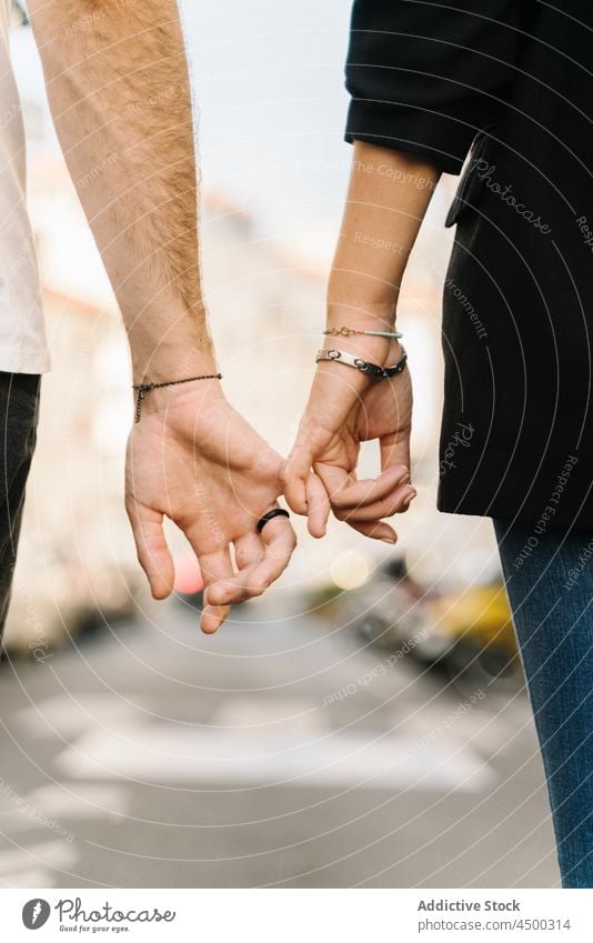 Anonymous couple holding little fingers while walking on city road street holding hands relationship love together romantic bonding affection spend time close