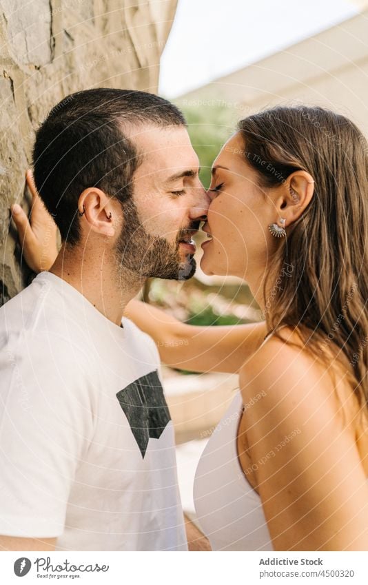 Loving ethnic couple kissing near wall of building on street embrace eyes closed love stone romantic relationship affection together city date boyfriend