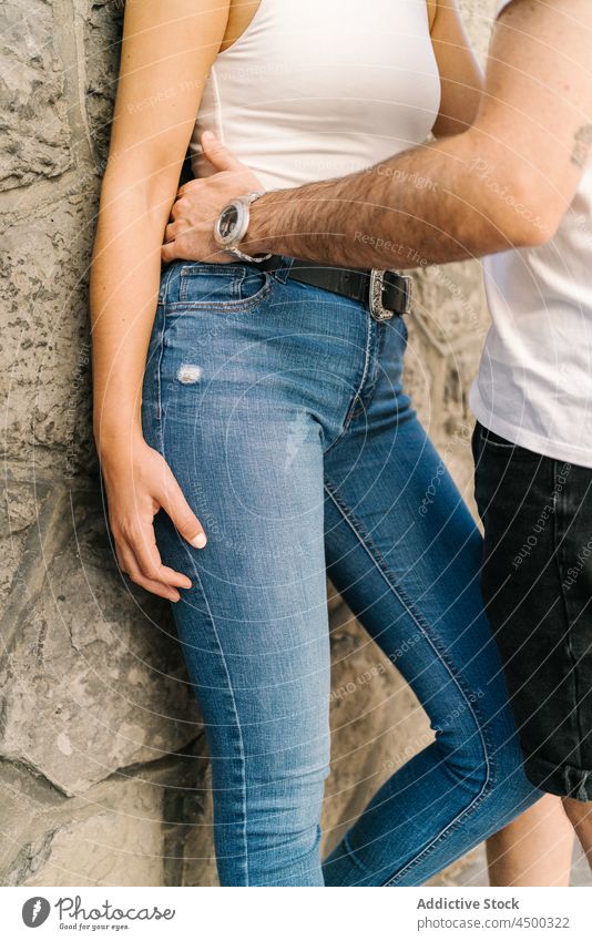 Anonymous amorous young Hispanic couple cuddling near aged stone wall in city embrace date love romantic relationship affection park together hug building