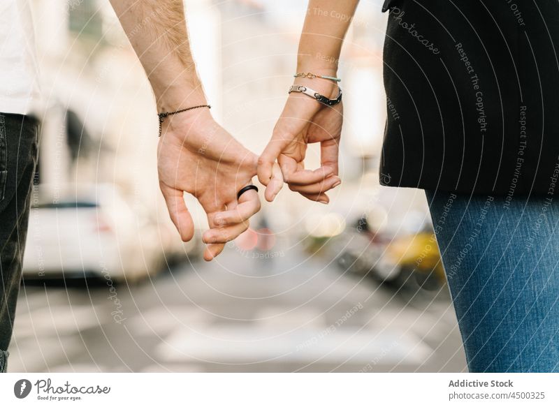 Anonymous couple holding little fingers while walking on city road street holding hands relationship love together romantic bonding affection spend time close