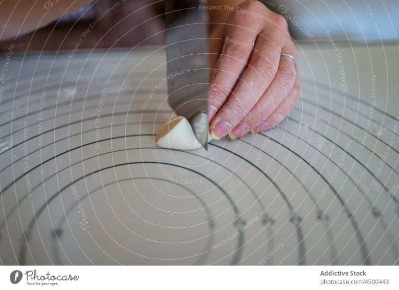 Unrecognizable woman cutting dough in kitchen while preparing dumplings prepare raw homemade cuisine culinary knife cook process female food table meal