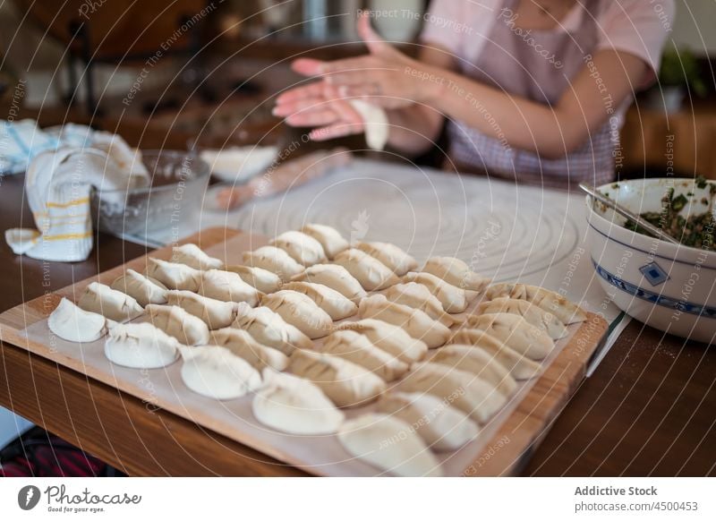 Crop housewife rolling dough with hands woman asian chinese cook kitchen cuisine dumpling homemade prepare food process recipe culinary female casual apron meal