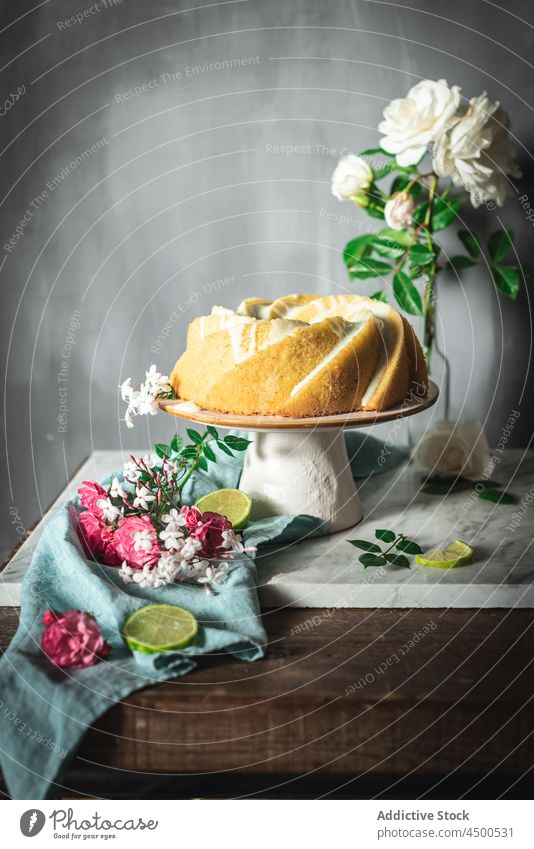 Lime sponge cake on plate near flowers and lime slices dessert confectionery citrus biscuit baked tasty fruit appetizing palatable culinary bakery composition