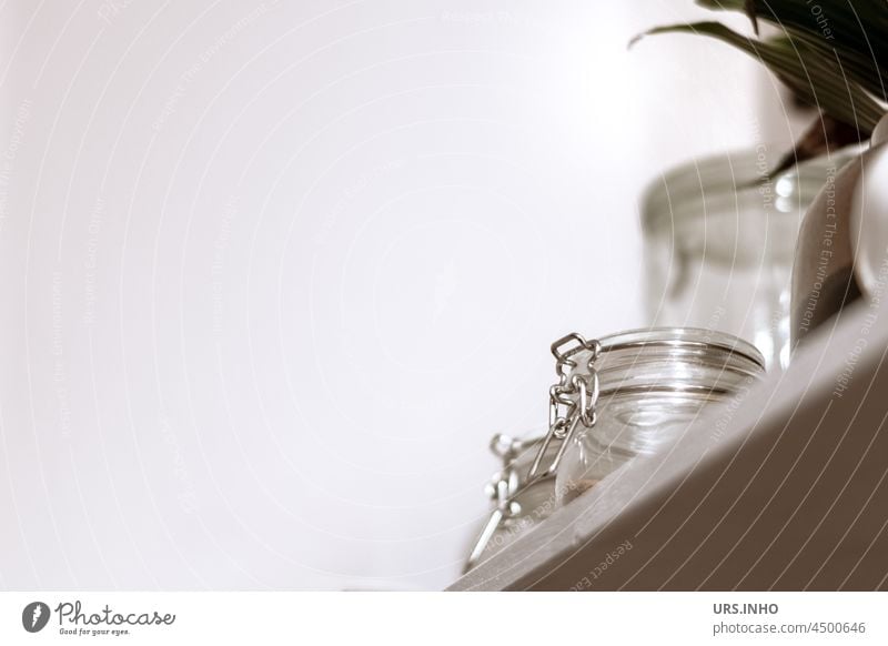 A white shelf in the kitchen with jars for stock and utensils to the right in the corner against a light wall with plenty of free space for text Shelves Kitchen