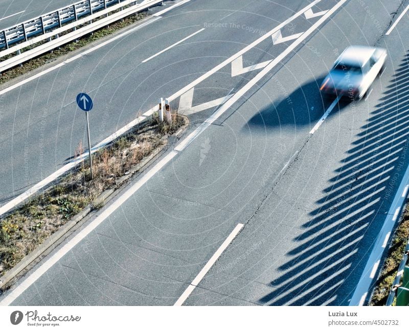 Straight ahead or going fast, on a fairly empty state highway in the sunshine. Line Sunlight Direction from on high Vehicle White Stripe mark Street