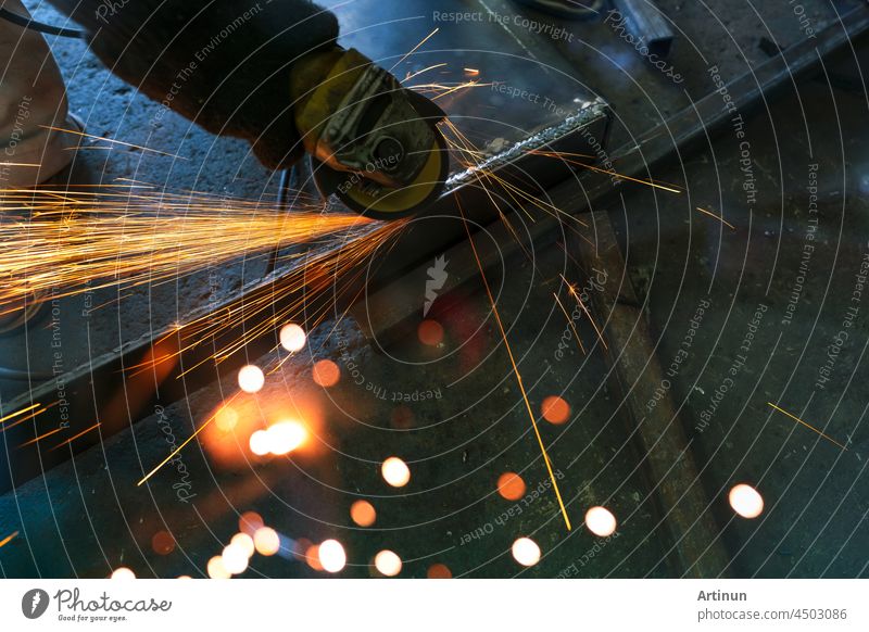 Industrial worker using angle grinder grinding metal on welding seams. Worker working with angle grinder and has sparks. Tool for cut steel. Safety in industrial workplace. Metal factory industry.