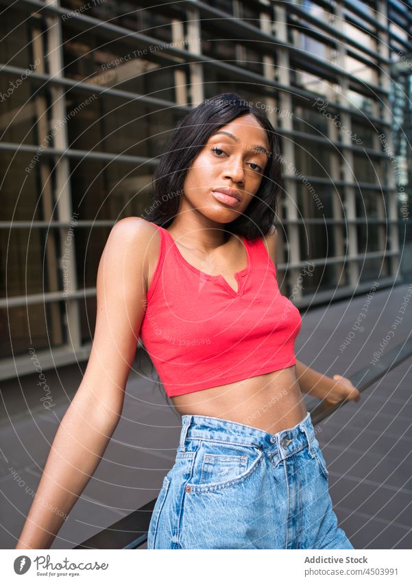 Stylish black woman leaning on railing in city street urban style building attire outfit modern female african american house attractive appearance lean on lady