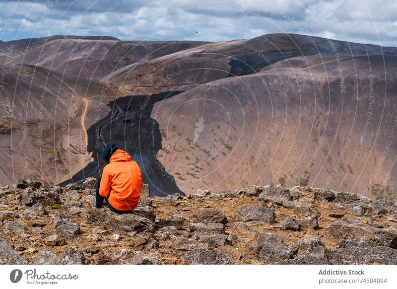 Anonymous traveler admiring landscape of volcano under cloudy sky nature scenery ground picturesque terrain formation hiker fagradalsfjall iceland lava rocky