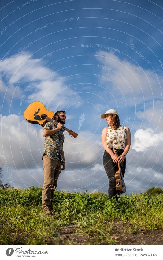 Musicians standing on green grass against blue sky in sunny day man woman guitar music acoustic instrument musician ukulele nature play male female summer