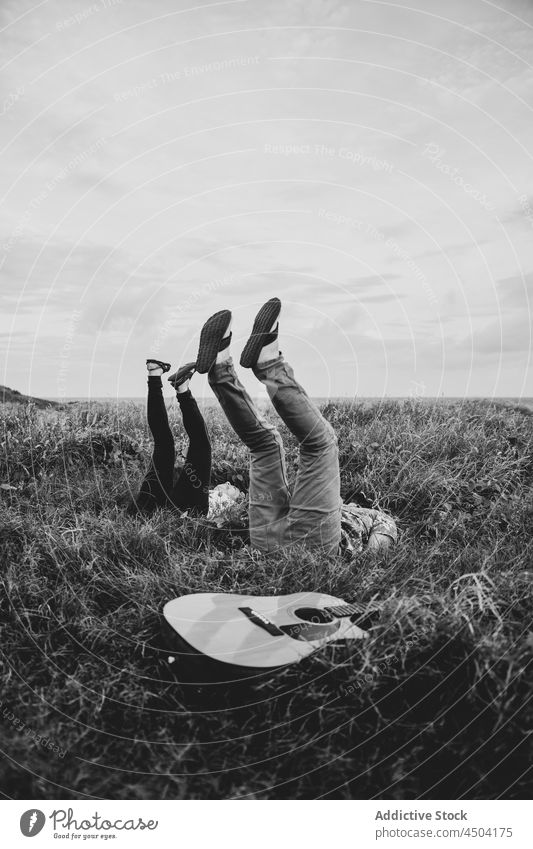 Friends lying with raised legs on grassy ground in nature friend field cheerful legs raised man countryside positive happy smile environment male daylight