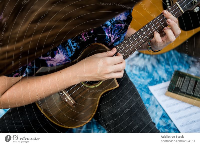 Anonymous woman musician playing ukulele on seashore in daylight instrument song talent beach sing female hobby nature melody perform sand enjoy daytime casual