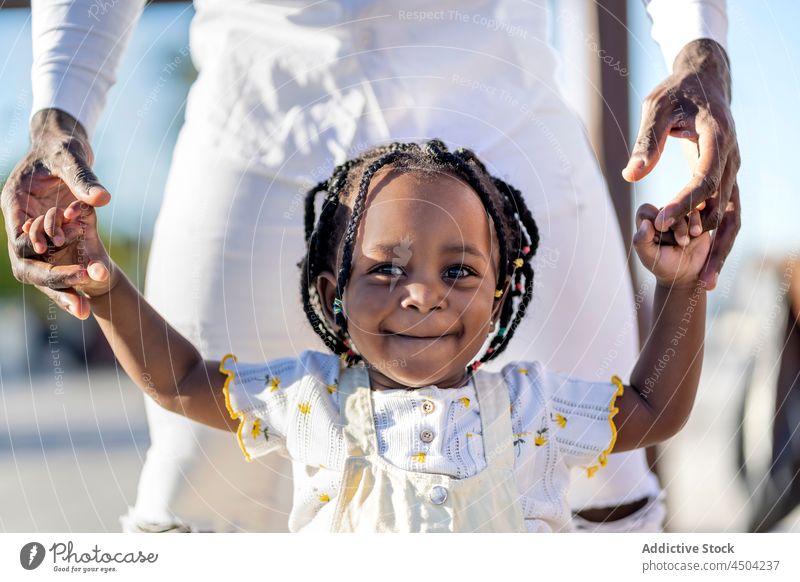 Smiling black girl walking with father on street happy child positive smile joy parent holding hands dad kid african american daughter childhood motherhood