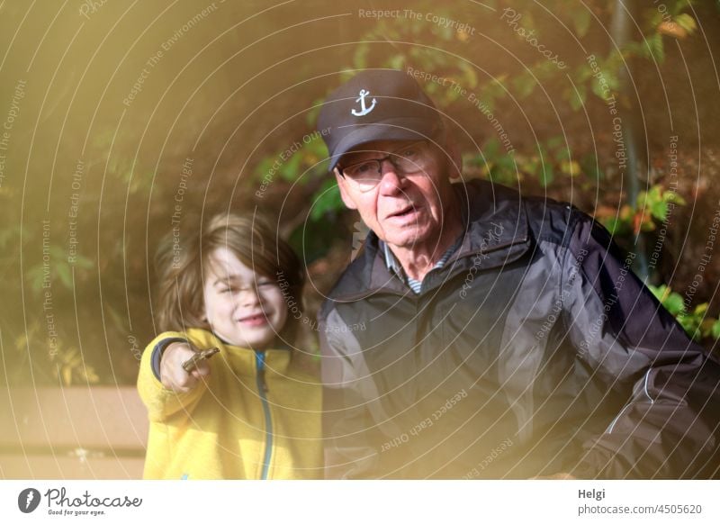 Grandpa and grandson sitting on a bench in the forest Human being Man Child Senior citizen Schoolchild Boy (child) Sit Break Forest out Smiling Joy Happy