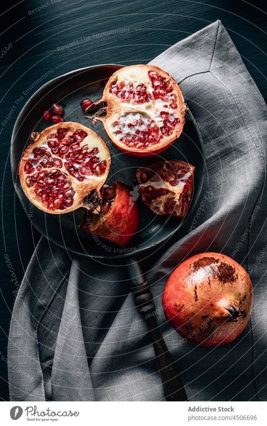 Ripe pomegranate on pan on table ripe fruit vitamin healthy food half seed chop kitchen tablecloth crumple whole tasty piece cut halved red slice creased grain