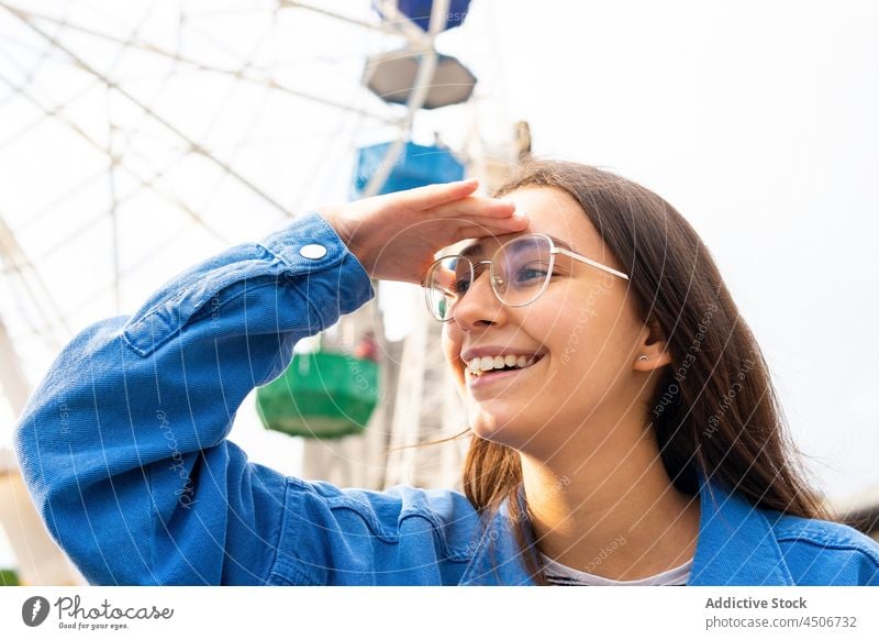 Cheerful woman looking away in amusement park excited explore curious smile happy cheerful ferris wheel fairground amazed pleasure vacation optimist style