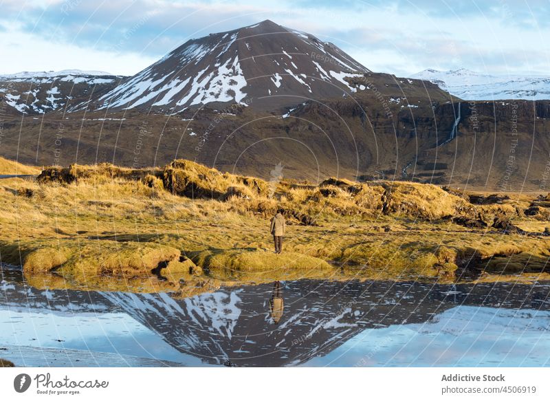 Anonymous male traveler admiring mountainous against blue sky man admire lake scenic landscape highland range nature recreation reflection snow casual alone