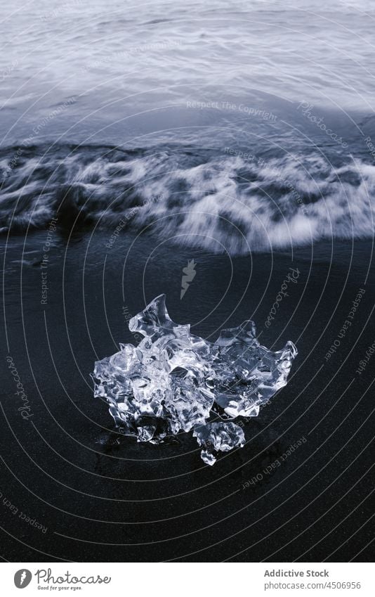 Glacier ice chunk on black sandy beach of wavy sea ocean glacier nature coastline seashore frozen cold iceland seascape motion surface climate idyllic shoreline