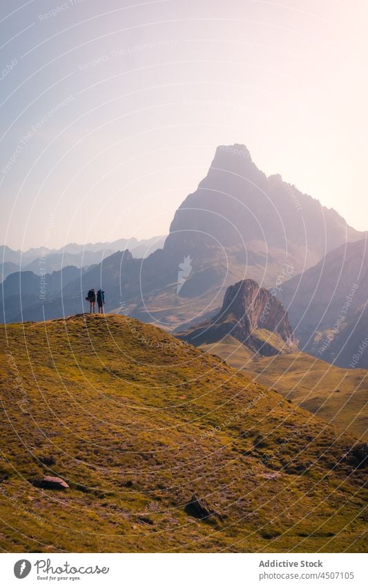 Unrecognizable travelers on edge of slope tourist mountain hill adventure nature journey hiker hilltop pyrenees spain environment scenery landscape wild