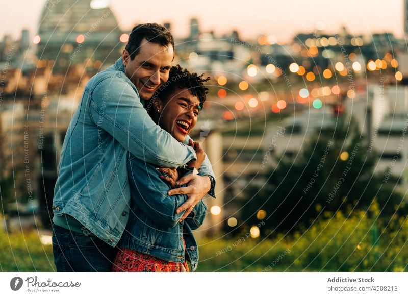 Loving multiethnic couple hugging on lawn relationship love caress city romantic date fondness street bonding embrace together girlfriend boyfriend building