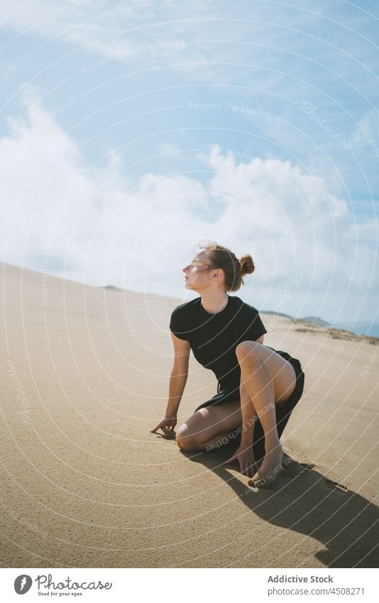 Woman squatting on sandy dune in arid valley woman desert exhausted hot freedom exotic dry heat female barefoot nature hill landscape environment extreme