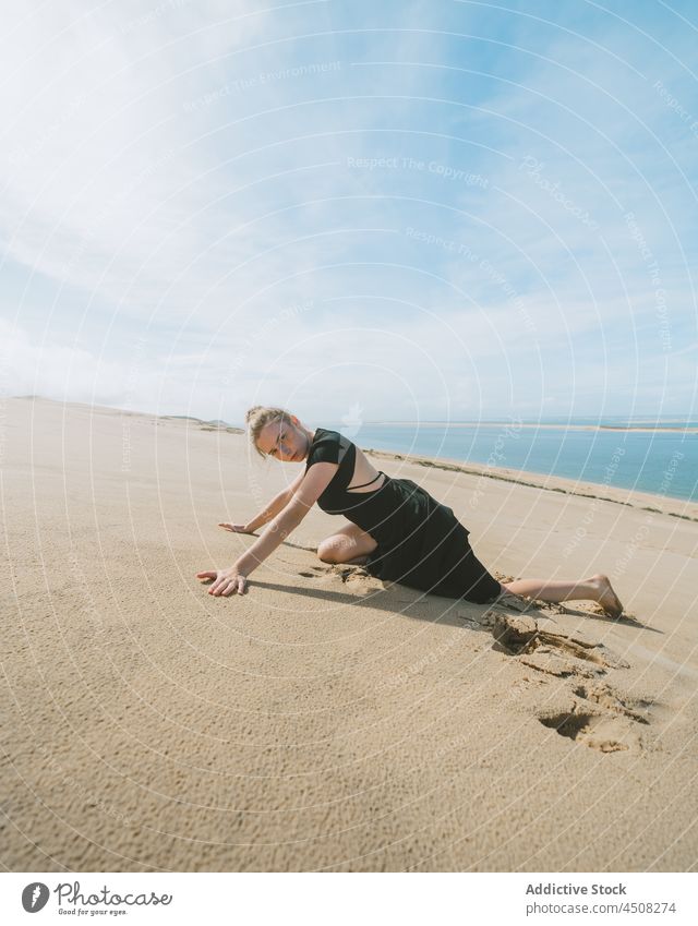 Graceful woman lying in sandy desert dune move grace posture flexible female motion stretch perform freedom ballet barefoot balance feminine young backbend art