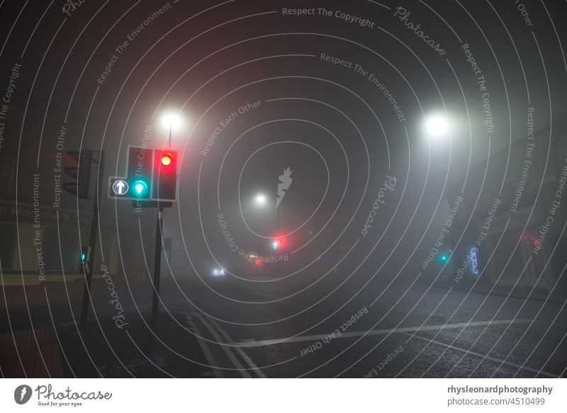 Incredibly thick fog at a cross road junction at broomhill, sheffield. Where fulwood road meets whitham road, and crookes road meets nile road. Traffic light shines in the foggy foreground. Dark night time scene.