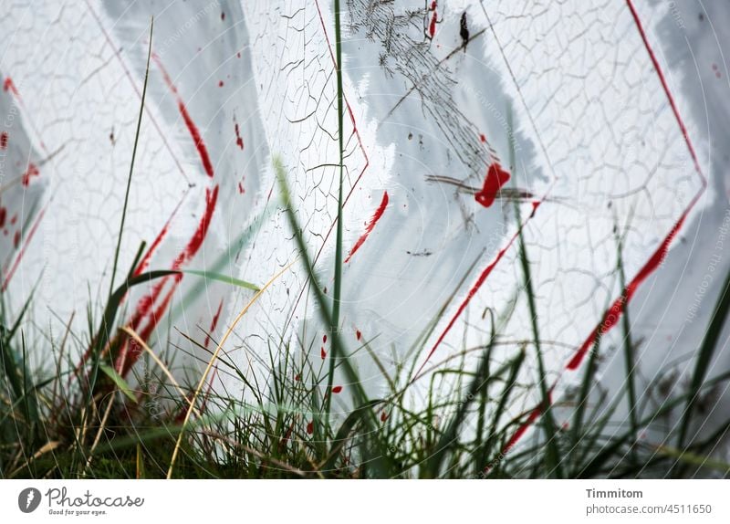 An aged sign shows the direction of travel Signs and labeling Arrow Direction Signage Orientation Navigation blades of grass Old Weathered Colour peeled off Red